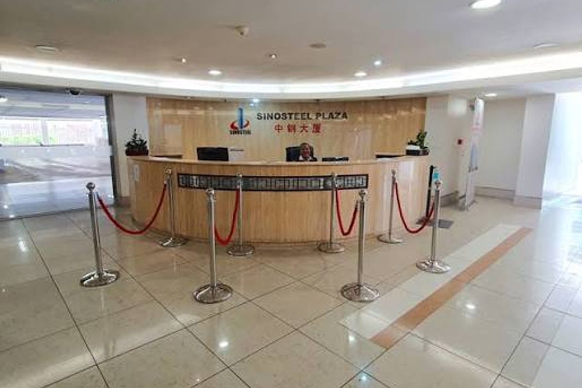 A professional commercial building reception area featuring a curved wooden reception desk, polished tiled flooring, and modern recessed cove lighting.