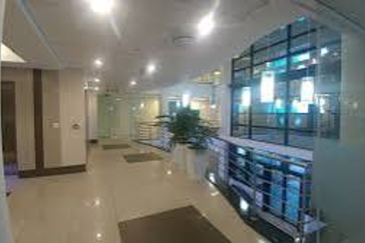 A spacious commercial hallway featuring polished tiled flooring, modern glass partitions, and recessed ceiling lighting, providing a professional and well-lit circulation area.