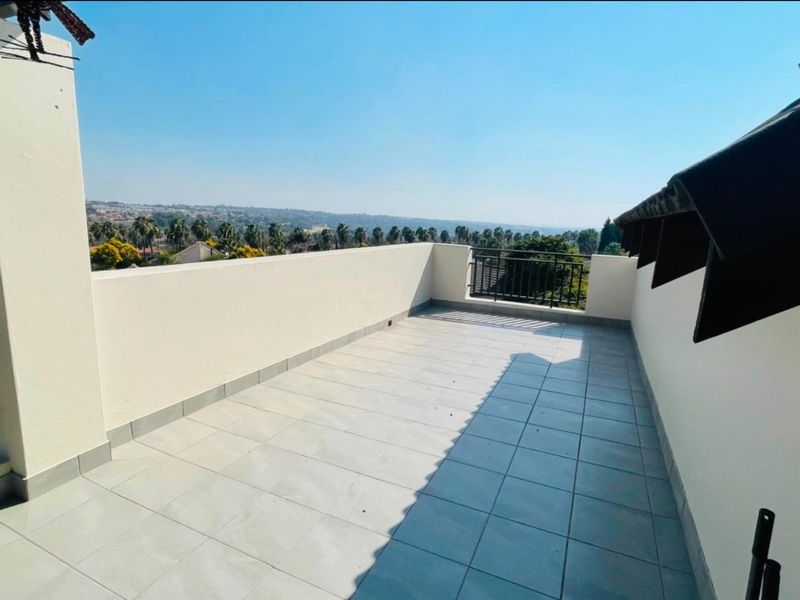 Spacious open-air balcony featuring tiled flooring, metal balustrades, and expansive elevated views of the surrounding landscape.