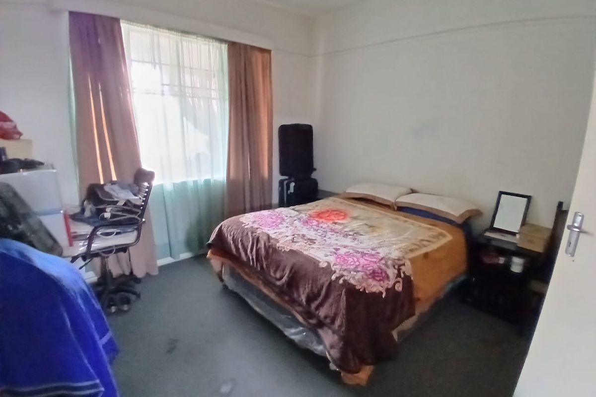 A standard bedroom featuring a window with curtain rails and carpeted flooring, requiring cosmetic updates to improve its overall appeal.