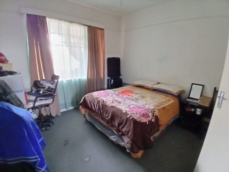 A standard bedroom featuring a window with curtain rails and carpeted flooring, requiring cosmetic updates to improve its overall appeal.