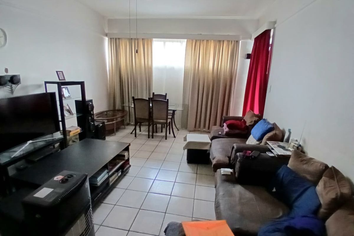 A spacious living area featuring tiled flooring and a ceiling fan, offering a functional layout with natural light from the window.