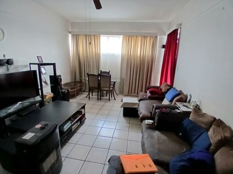 A spacious living area featuring tiled flooring and a ceiling fan, offering a functional layout with natural light from the window.