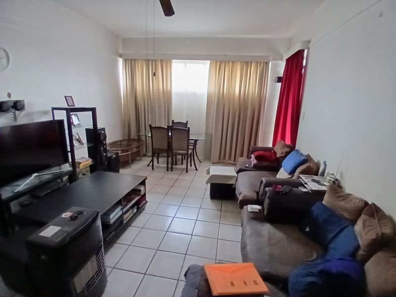 Open-plan living and dining area featuring tiled flooring and a ceiling fan, providing a functional space for relaxation and meals.