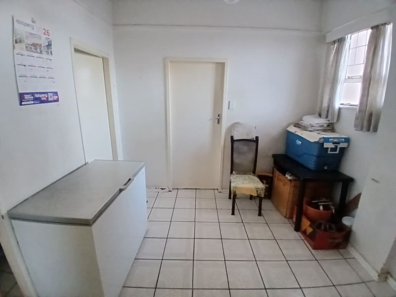 A functional utility or storage space featuring tiled flooring and a window with security bars, offering potential for organization or renovation.