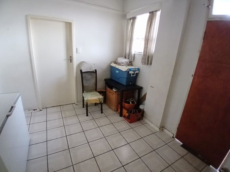 A functional utility space featuring tiled flooring and natural light, suitable for storage or laundry conversion.