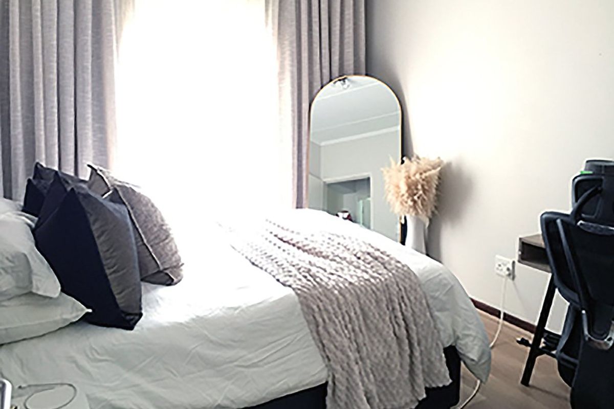 A well-lit bedroom featuring laminate flooring and neutral wall finishes, providing a comfortable and functional living space.