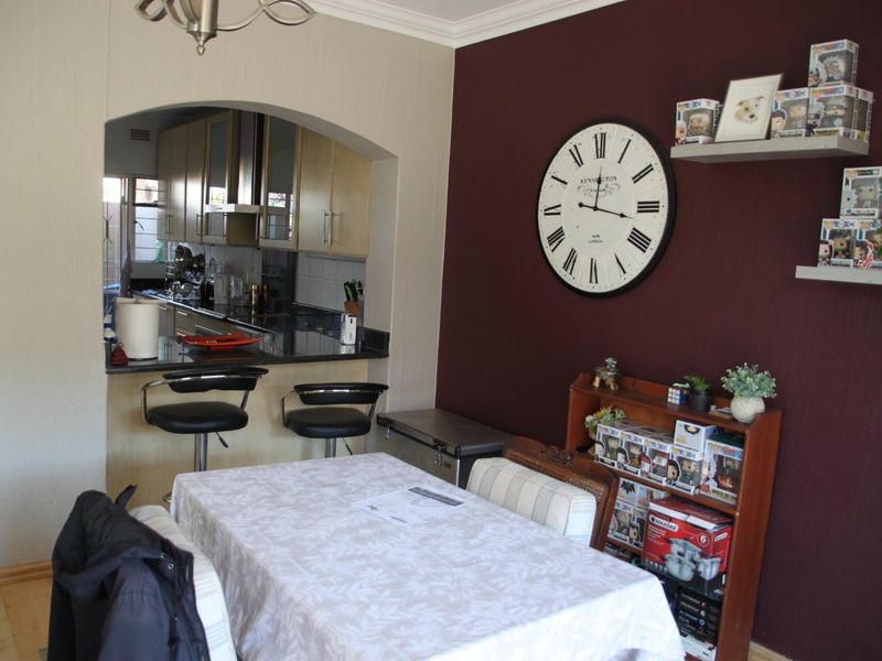 Open plan dining area featuring an arched opening to the kitchen with granite countertops and laminate flooring.