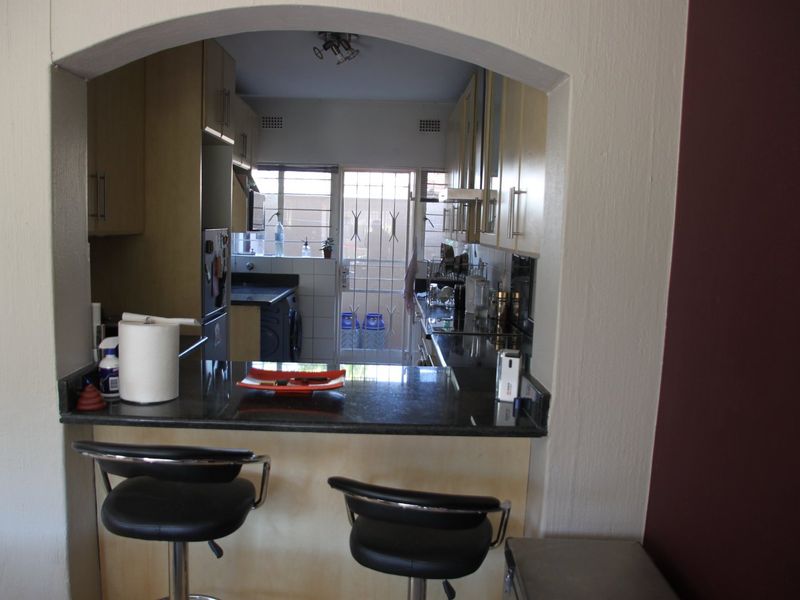 A functional kitchen featuring granite countertops, built-in cabinetry, and a breakfast bar, viewed through a classic architectural archway.