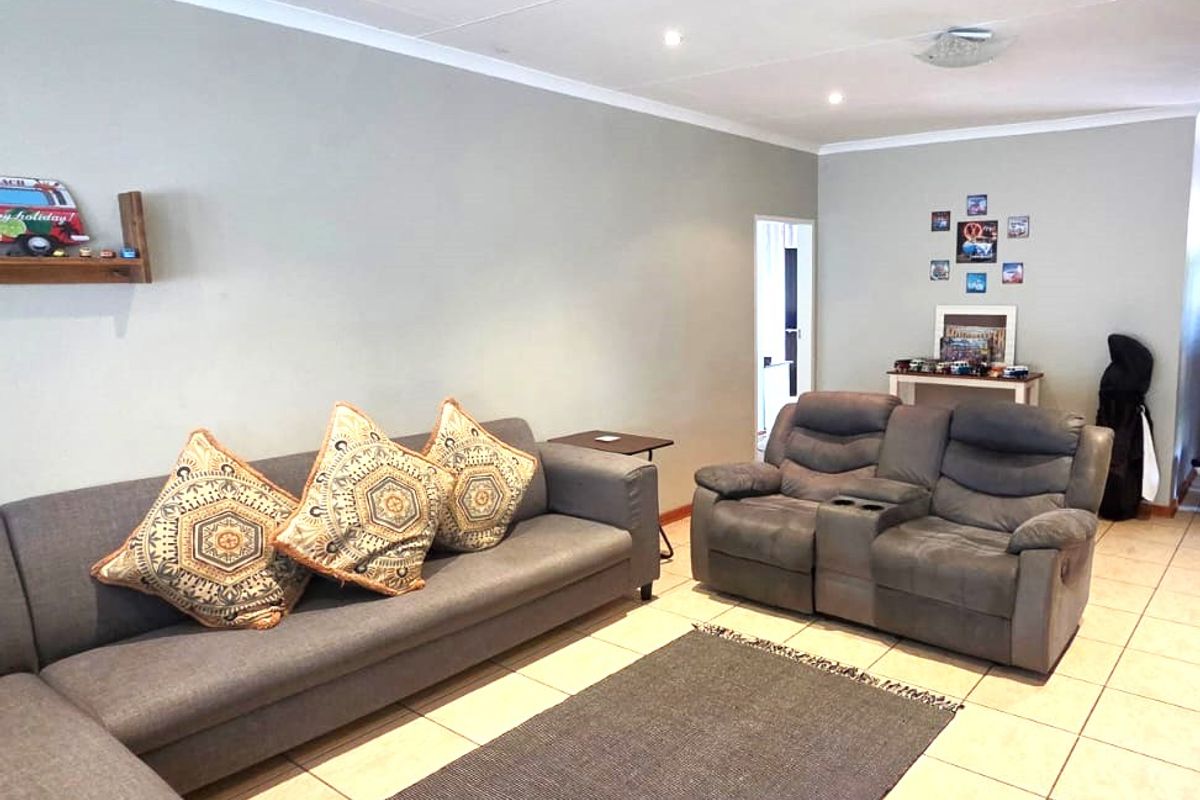 A spacious living room featuring neutral wall tones, tiled flooring, and recessed ceiling lighting, providing a comfortable and functional area for relaxation.