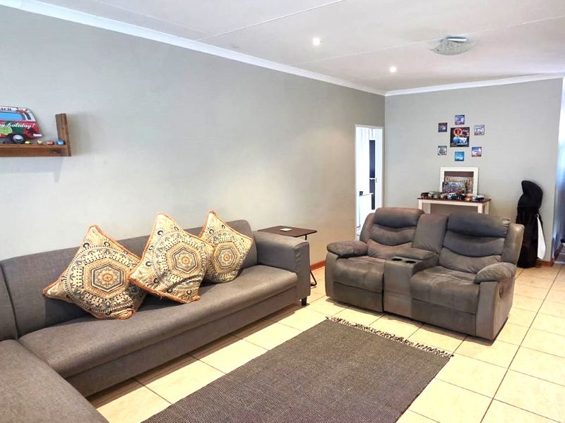 A spacious living room featuring neutral wall tones, tiled flooring, and recessed ceiling lighting, providing a comfortable and functional area for relaxation.
