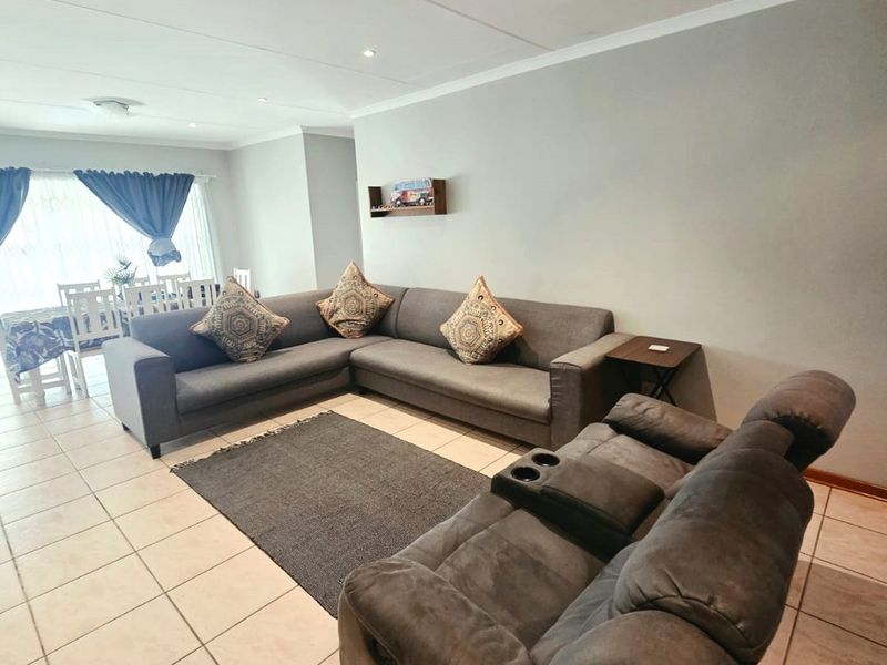 Spacious open-plan living and dining area featuring neutral tiled flooring, recessed downlighting, and a clean, functional layout.