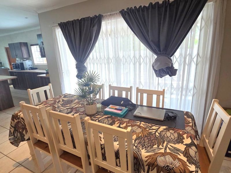 Open plan dining area featuring tiled flooring and a security gate, with a view into the adjacent kitchen space.