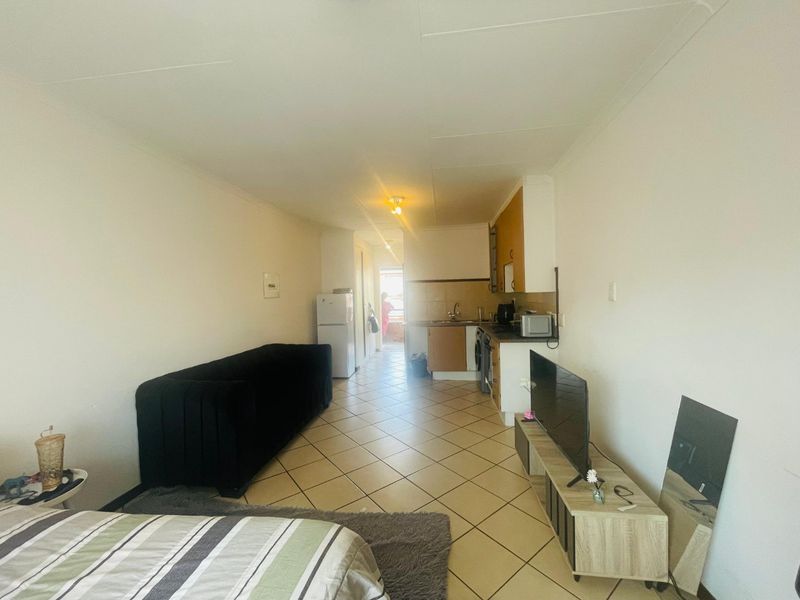 Open-plan living area featuring a compact kitchen with built-in cabinetry and tiled flooring throughout.