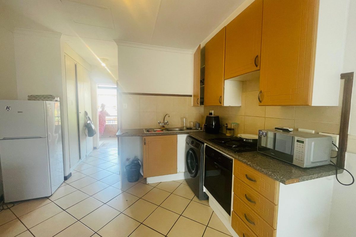 A functional kitchen featuring built-in cabinetry, laminate countertops, a built-in oven, and tiled flooring, offering a practical layout for daily use.
