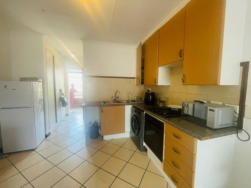 A functional kitchen featuring built-in cabinetry, laminate countertops, a built-in oven, and tiled flooring, offering a practical layout for daily use.