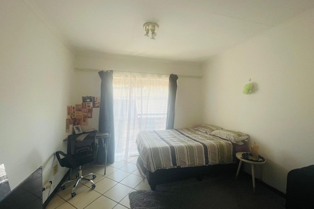 A functional bedroom featuring tiled flooring and a sliding glass door that provides natural light and access to the exterior.