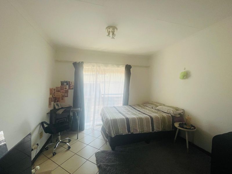 A functional bedroom featuring tiled flooring and a sliding glass door that provides natural light and access to the exterior.