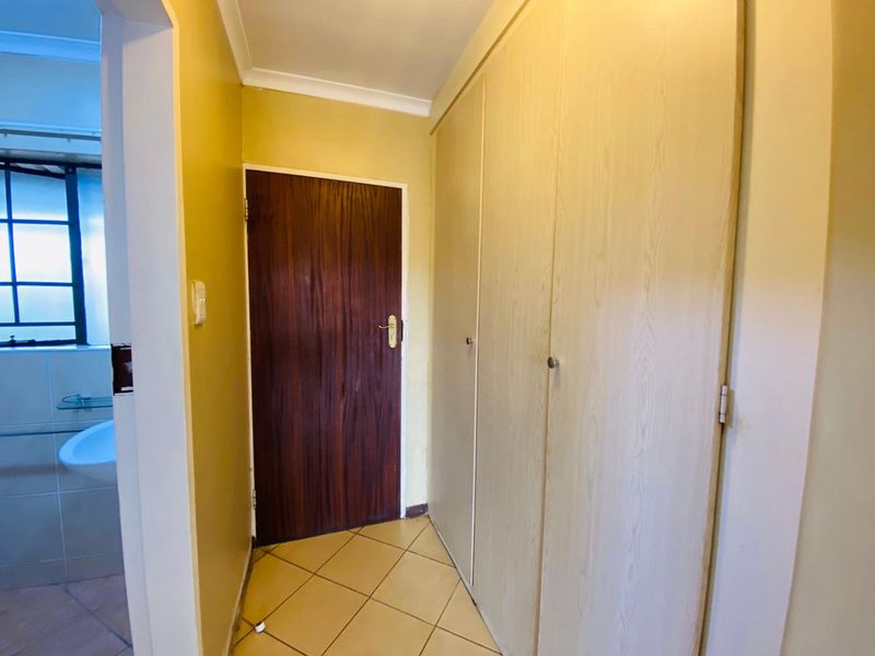 A functional hallway featuring built-in storage cupboards, tiled flooring, and access to an adjacent bathroom.