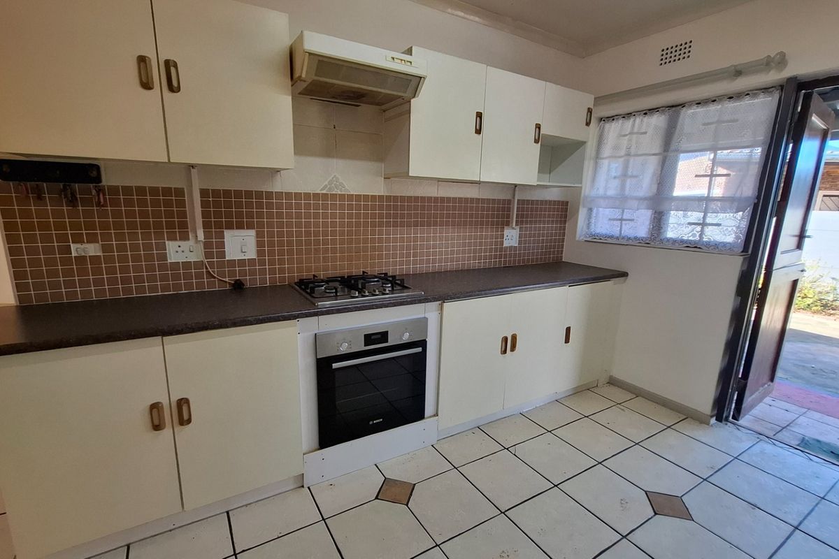 A functional kitchen featuring built-in cabinetry, a gas hob, an integrated oven, and a tiled backsplash with direct access to the exterior.