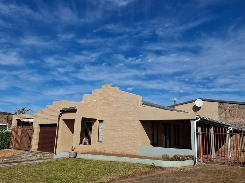 Front elevation of a single-story house featuring a garage, covered patio area, and secure perimeter fencing under a clear blue sky.