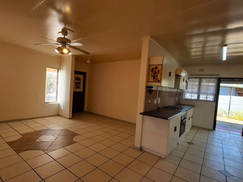 Open-plan living and kitchen area featuring tiled flooring, built-in cabinetry, and a gas hob, offering a functional layout ready for modernization.