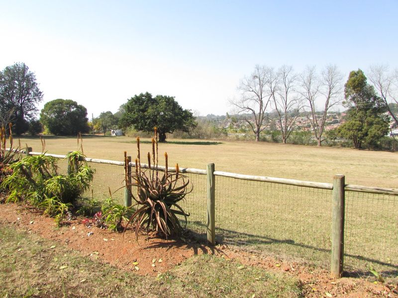A spacious farm garden area featuring established aloe plants and secure timber post and wire mesh fencing overlooking open land.