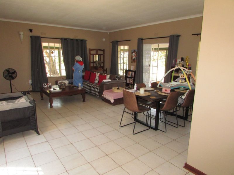 Spacious open-plan living and dining area featuring neutral wall tones, tiled flooring, and multiple access points to the exterior through sliding glass doors.