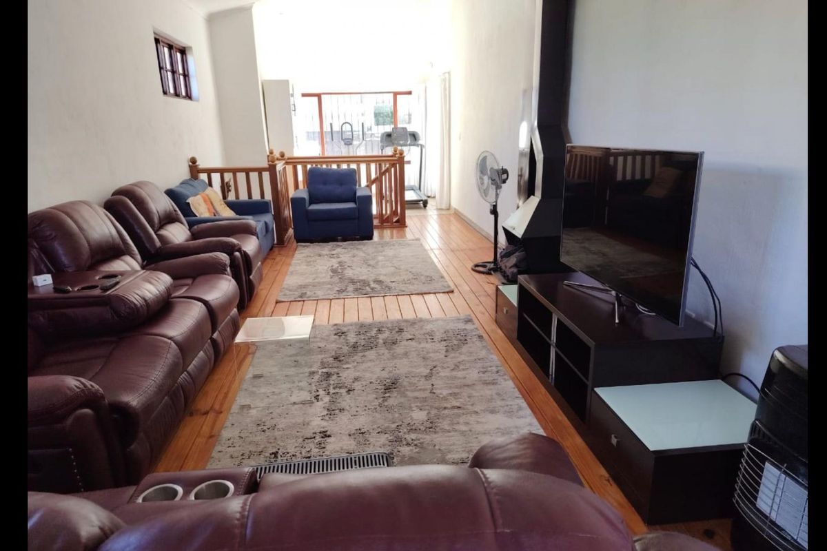 Spacious living room featuring hardwood flooring, a modern freestanding fireplace, and a timber balustrade leading to an adjacent area.