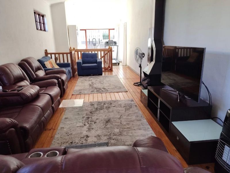 Spacious living room featuring hardwood flooring, a modern freestanding fireplace, and a timber balustrade leading to an adjacent area.
