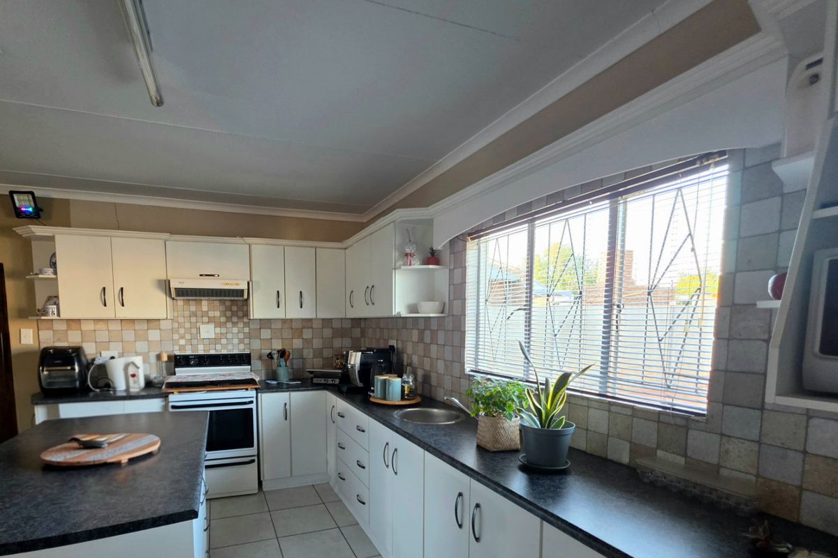 Functional kitchen featuring white cabinetry, dark laminate countertops, tiled backsplash, and a freestanding stove with an extractor fan.