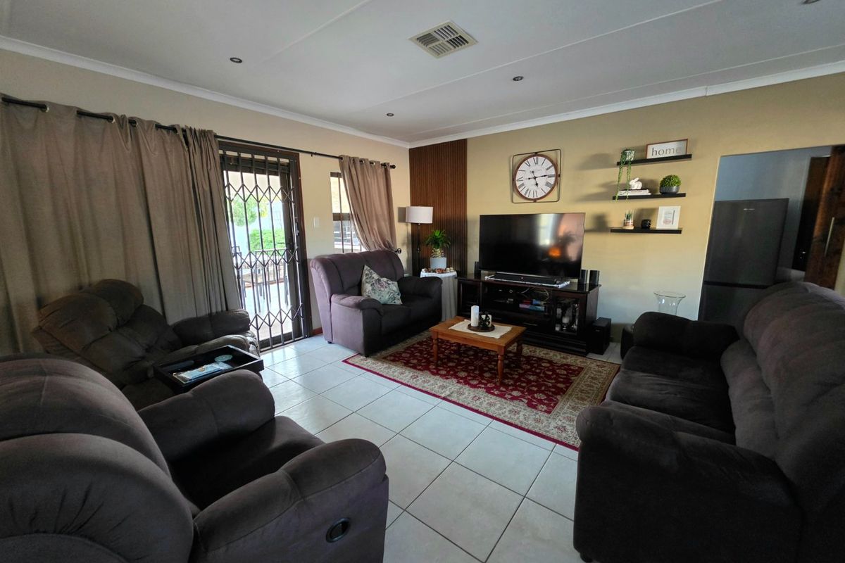 A comfortable living room featuring tiled flooring, recessed lighting, and a decorative feature wall, with direct access to the outdoor area via a sliding door.