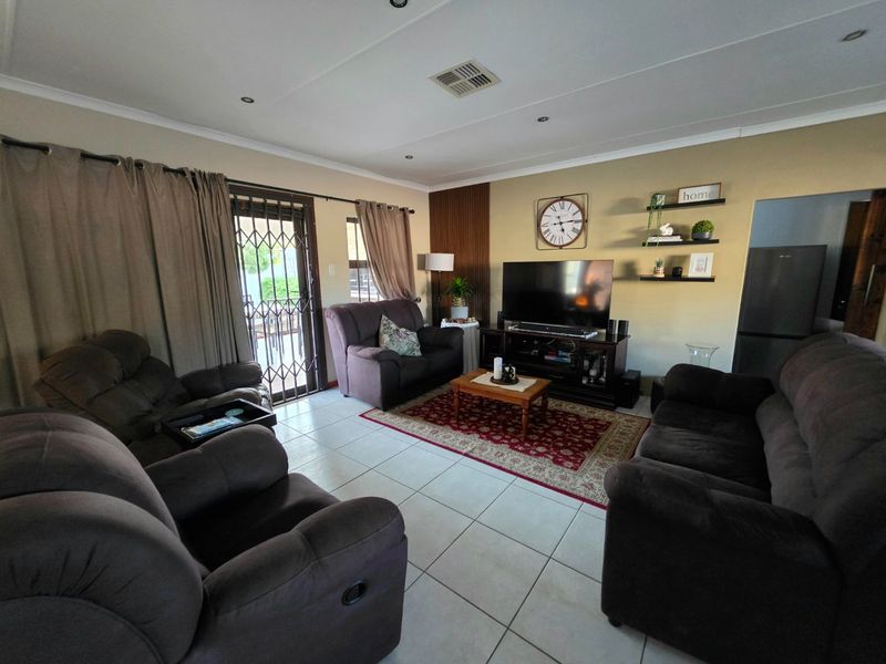 A comfortable living room featuring tiled flooring, recessed lighting, and a decorative feature wall, with direct access to the outdoor area via a sliding door.