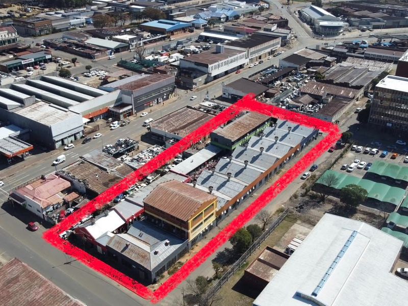 Aerial view of a commercial property complex featuring multiple buildings with corrugated metal roofing, situated within an established industrial and commercial urban area.