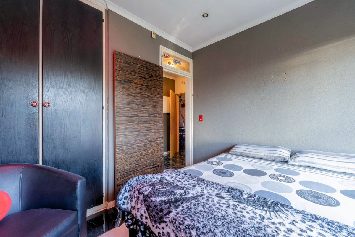 A bedroom featuring built-in cupboards, recessed downlighting, and coving, with access to an adjoining room.