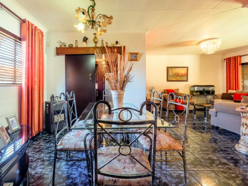 Open plan dining and living area featuring dark tiled flooring and integrated lighting, providing a versatile space for family gatherings and daily living.