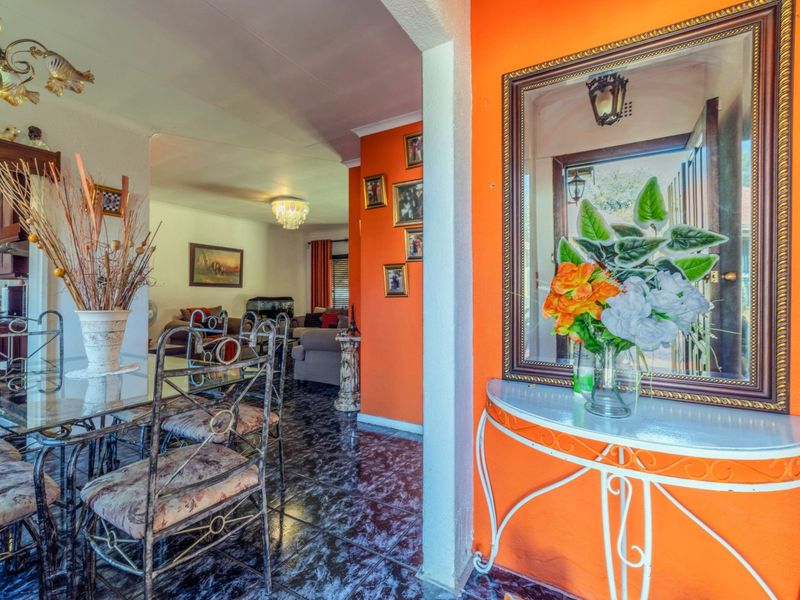 An open-plan living and dining area featuring tiled flooring and a distinct orange accent wall, creating a connected flow between the spaces.