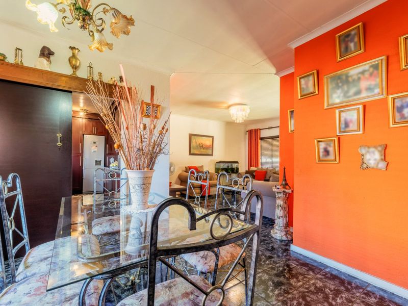 Open plan living and dining area featuring tiled flooring and a bright accent wall, connecting to a kitchen space.