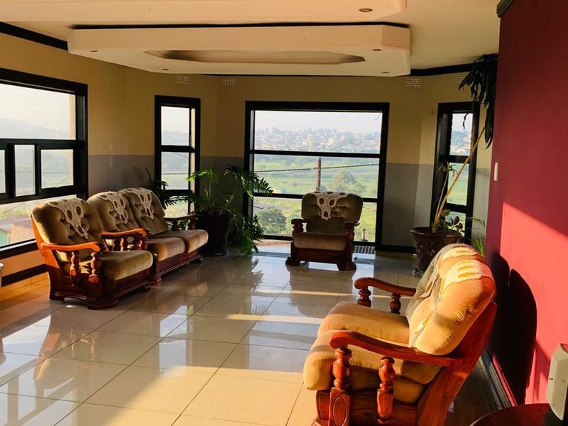 Spacious living room featuring large windows with scenic views, tiled flooring, and a decorative recessed ceiling design.