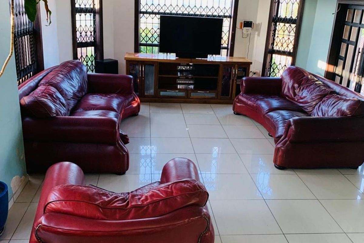 Spacious living room featuring large format floor tiles, recessed ceiling lighting, and security gates on windows.