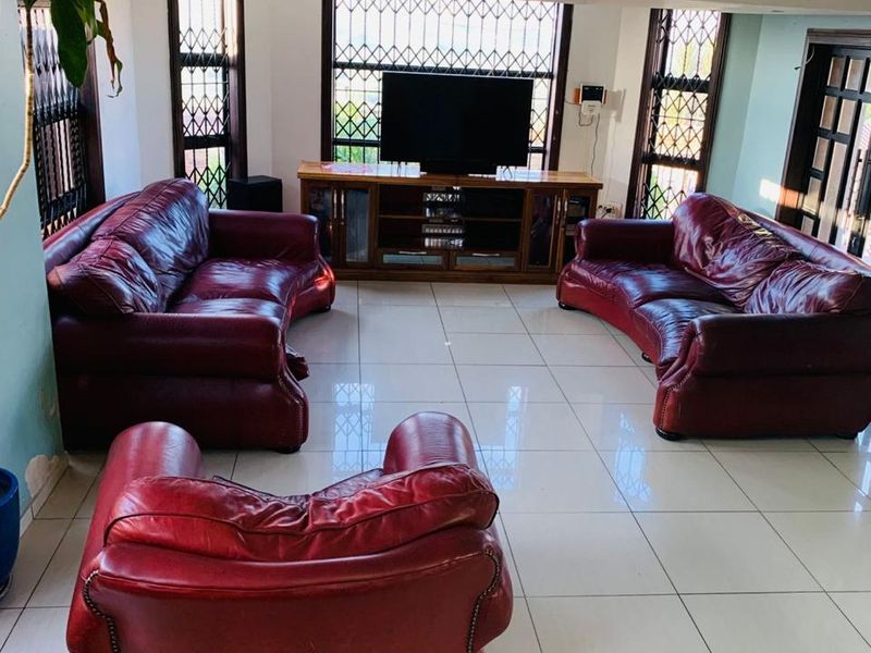 Spacious living room featuring large format floor tiles, recessed ceiling lighting, and security gates on windows.
