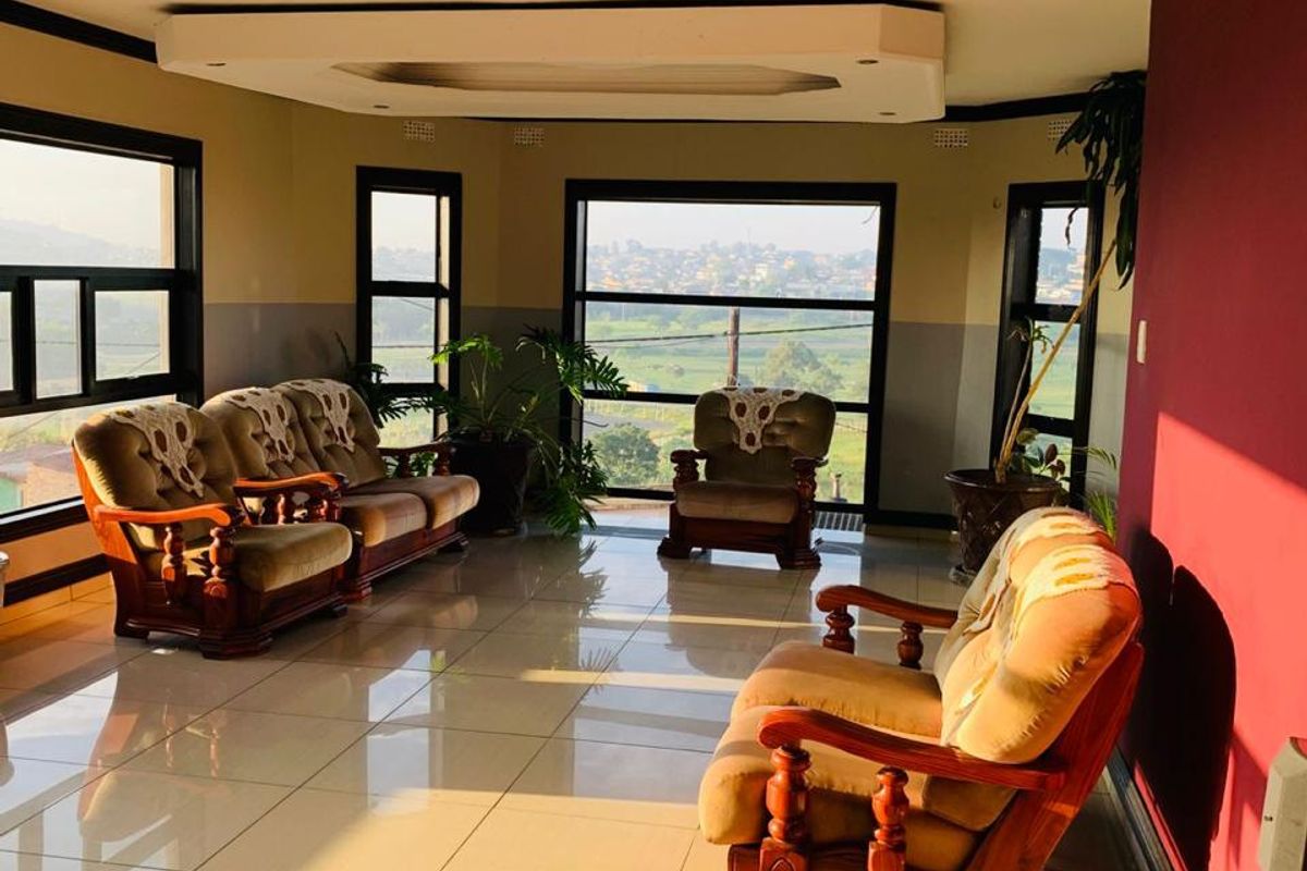Spacious living room featuring large windows with scenic views, tiled flooring, and a decorative recessed ceiling design.