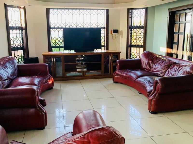 Spacious living room featuring tiled flooring, a coffered ceiling with recessed lighting, and large windows fitted with security bars.