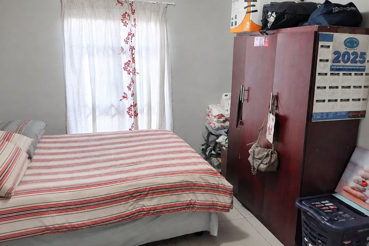 A functional bedroom featuring tiled flooring and a window with a curtain rod, providing a neutral base for personalization.