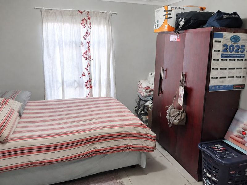 A functional bedroom featuring tiled flooring and a window with a curtain rod, providing a neutral base for personalization.