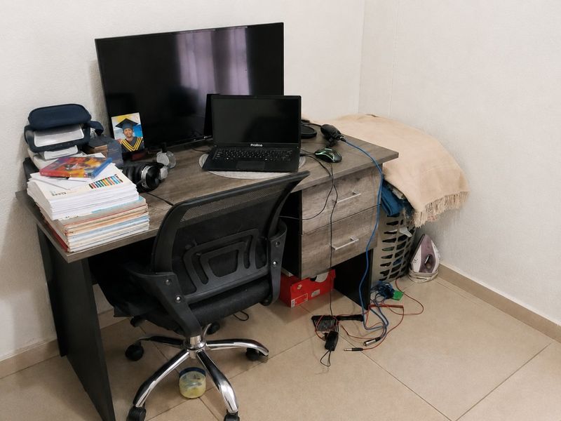 A corner space currently utilized as a home office area with tiled flooring.
