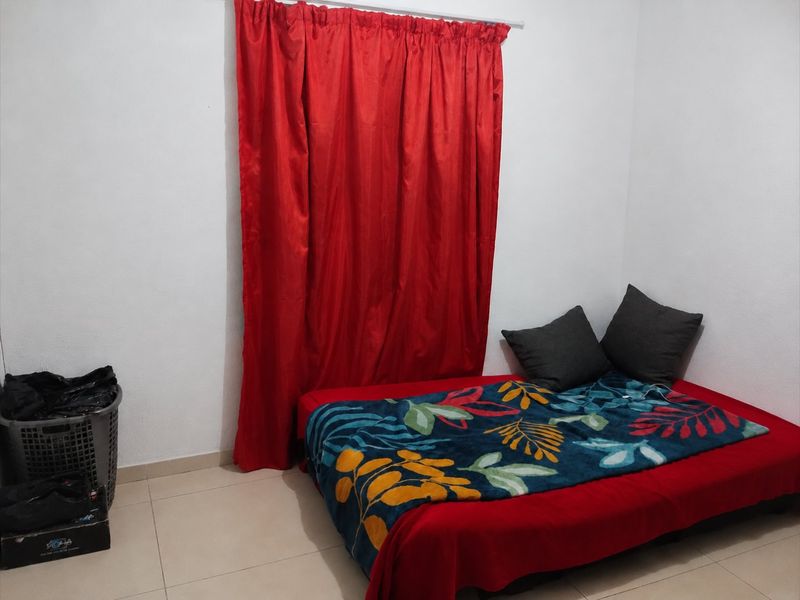 A simple bedroom featuring tiled flooring and a window with a curtain rod, providing a functional space ready for personalization.