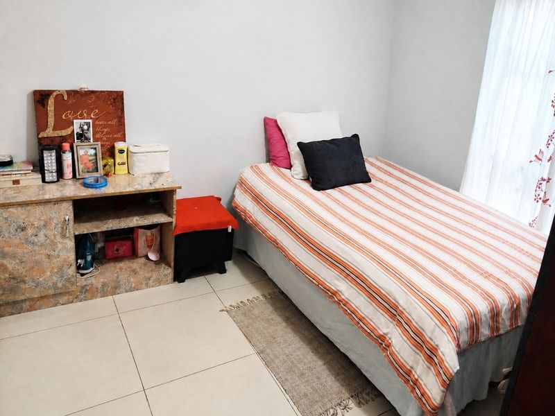 A functional bedroom featuring tiled flooring and built-in cabinetry, providing a clean and simple living space.
