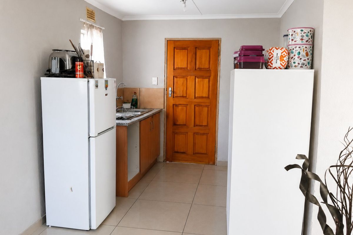 A functional kitchen area featuring tiled flooring, wooden cabinetry, and a solid timber door, providing a practical space for food preparation.