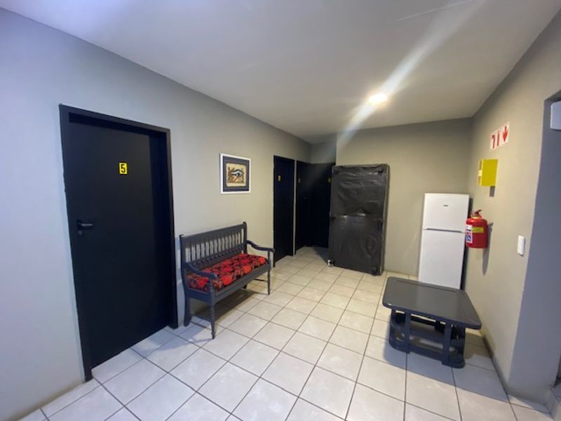A functional hallway featuring tiled flooring, multiple doorways, and essential fire safety equipment including an extinguisher and signage.